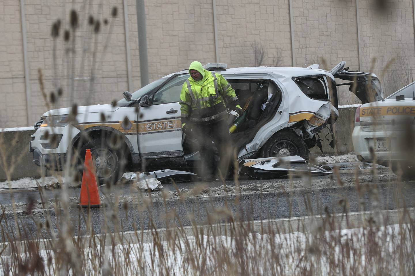 A towing company employee looks through the wreckage of an Illinois State Police vehicle involved in a crash on Monday, Feb. 15, 2021, at I55 North and US Rt. 30 in Joliet, Ill. A cash on I55 northbound resulted in an Illinois State Police being airlifted to a nearby hospital and the expressway shut down for hours.