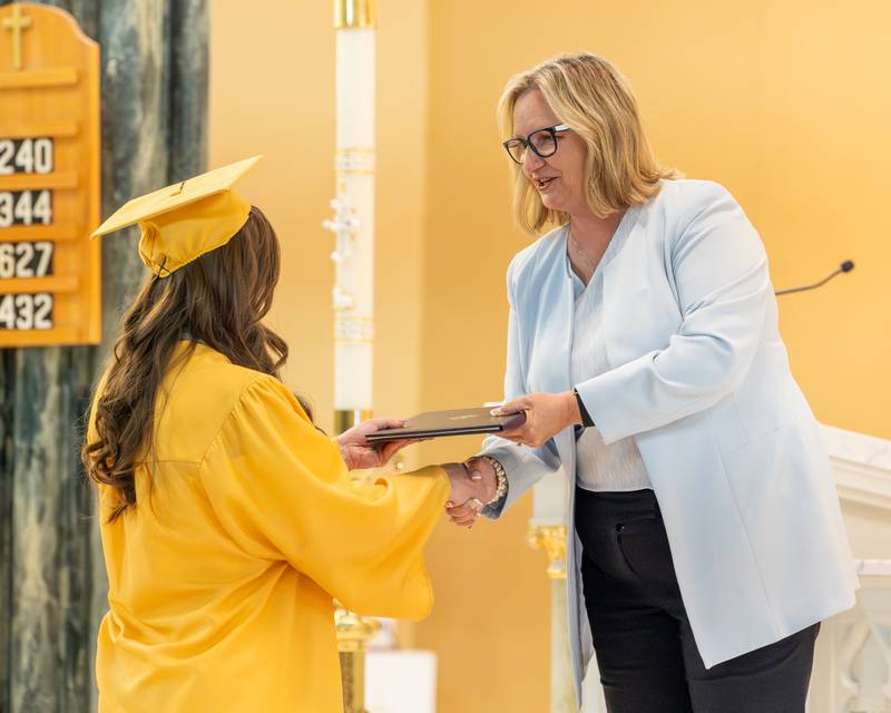 Illinois Valley Community College President Dr. Tracy Morris hands Salutatorian and IVCC graduate Serenity Guzman IAI General Education Certification at the Class of 2026 Marquette Academy Graduation Ceremony on May 24, 2026 at St. Columba Church in Ottawa.