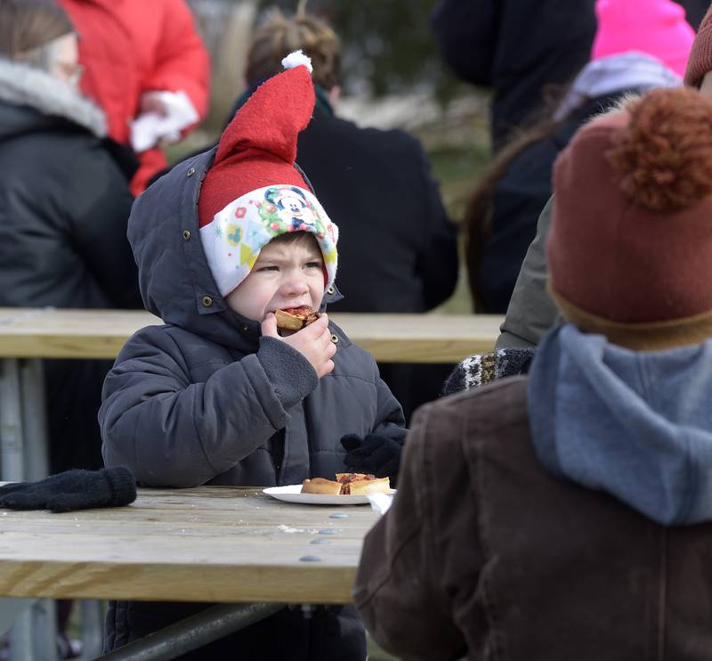 Despite the frigid temperatures, Gabriel Anderson stays warm by sampling a hot pizza Saturday, Nov. 30, 2024, during the Chris Kringle Market in Ottawa. The market will run every Friday, Saturday and Sunday through Dec. 22.