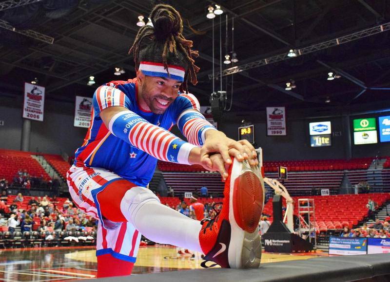 Harlem Globetrotters showman Hammer Harrison stretches during Thursday night's show at the NIU Convocation Center. Harrison is 6 foot, 9 inches tall and holds the Guinness World Records record for the longest underhand basketball shot at 85 feet, 4.25 inches away from the basket.