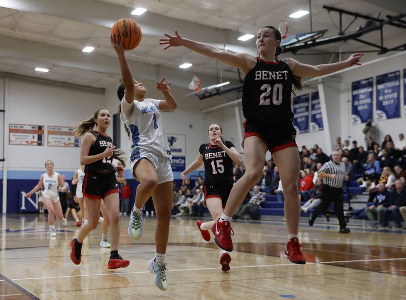 Benet's Sailer Jones (20) goes airborne to defend Nazareth's Allia Von Schlegell (1) during a girls varsity basketball game between Benet and Nazareth academies on Saturday, Dec. 14, 2024 in La Grange Park.