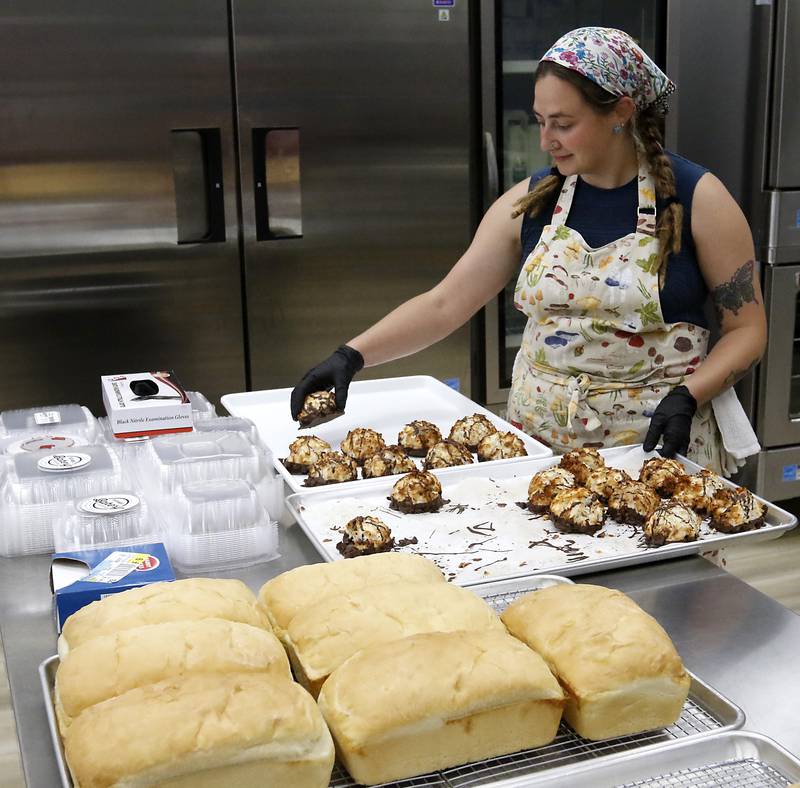 Sara Bartyzel moves coconut macrons to a display tray on Friday, June 27, 2025, at the recently opened Black Market Bakery in downtown Crystal Lake.