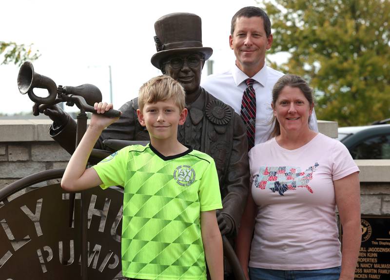 Sam Schwartz, 10, a fifth grader from North Grove Elementary School in Sycamore, and his mom Marcy and dad Nathan with the Wally Thurow statue Friday Sept. 27, 2024, in Sycamore. Sam was the theme contest winner for the 2024 Sycamore Pumpkin Festival.