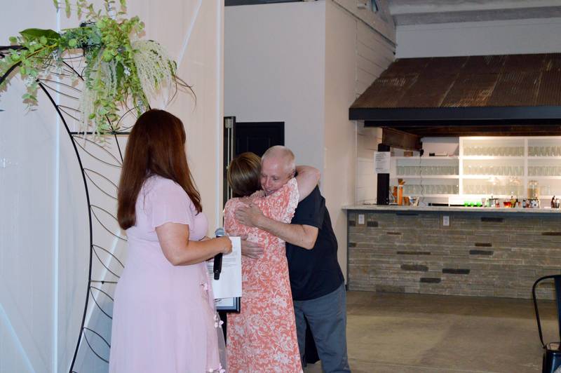 Oregon Area Chamber of Commerce 2022 Citizen of the Year John Lindhorst hugs Lori Peterson while Chamber Executive Director Liz Vos looks on. Peterson presented Lindhorst with the award at the Chamber's annual awards dinner. The event took place Aug. 18 at River's Edge Experience.