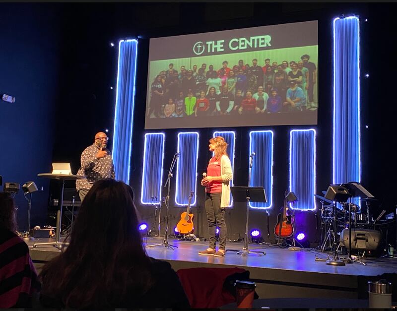 Nate Smith, pastor of The Table in Joliet (left), stands on the church's stage with Kelly Corcoran, director of The Center, and prays over the youth in attendance. The Center is a nonprofit organization that ministers to teens and young adults. It meets on Thursday nights at The Table.