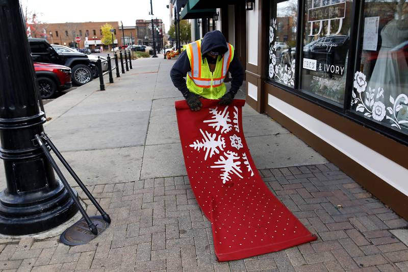 A city of Woodstock employee prepares a snowflake banner while installing holiday decorations Tuesday, Nov. 12, 2024, around the historic Woodstock Square. Workers are preparing the Square for the city's annual Lighting of the Square event on Friday, Nov. 29.