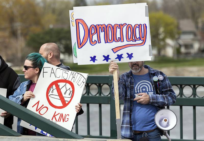 Protestors line the edges of the Galena Avenue bridge in Dixon Saturday, April 19, 2025, voicing their opinion of President Trump and their feelings the administration is not following a Democracy based government.