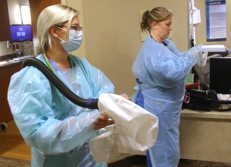 March 22, 2021 File photo - Nurse Teague Mallar, (left) and charge nurse Angie Bogle put on personal protective equipment Friday in the Intermediate Care Unit at Northwestern Medicine Kishwaukee Hospital in DeKalb.