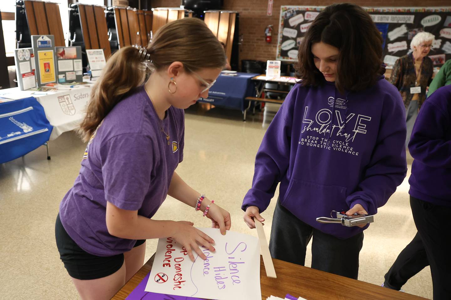 Gabby Tancl and Cori Monaco make a sign for the Joliet Junior Women’s Club table at the Take Back the Night event at Hufford Junior High on Thursday, Oct. 5, 2023 in Joliet.