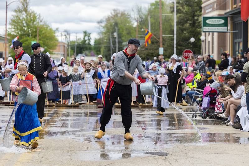 The annual cleaning of the streets kicks off the 51st Fulton Dutch Days parade Saturday, May 3, 2025. Dressed in traditional Dutch garb, volunteers throw water and scrub the streets ahead of the parade marchers.