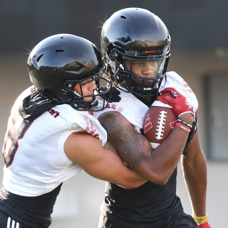 Northern Illinois Huskies wide receiver Trayvon Rudolph (right) carries the ball as wide receiver Kacper Rutkiewicz tries to knock it loose during a ball security drill at the teams first practice of the season Wednesday, Aug. 2, 2023, at Huskie Stadium in DeKalb.