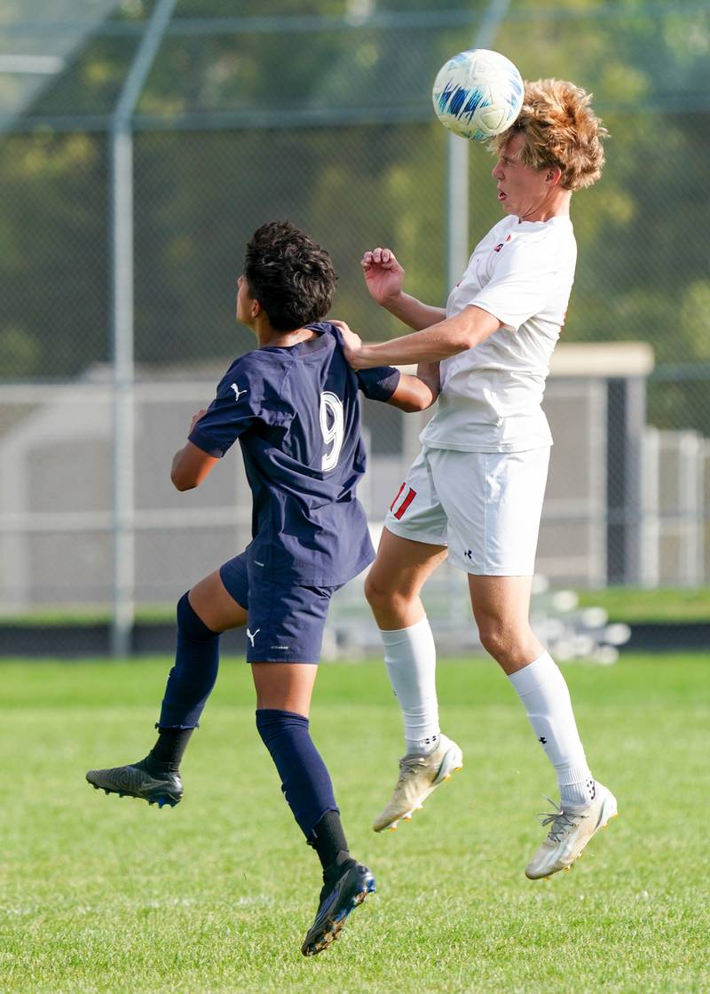 Oswego’s Nolan Gustafson (11) heads the ball over Oswego East's Jonathan Carranza (9) during a soccer match at Oswego East High School on Tuesday, Sept. 26, 2023.