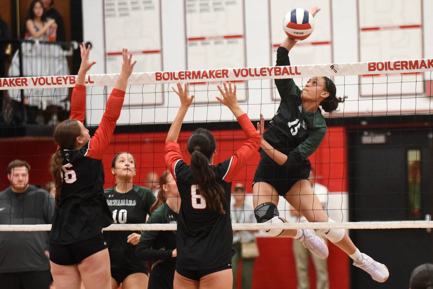 Bishop McNamara's Jersey Slone, right, leaps to send a hit over the net as Bradley-Bourbonnais' Liv Woolman, left, and Hannah Wojnowski prepare to block during All-City action at Bradley-Bourbonnais Wednesday, Sept. 10, 2025.