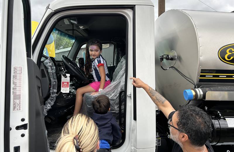 Victoria Ramirez, 7, of Oregon, climbs behind the wheel of an E.D. Etnyre truck as Leo Rivera, an Etnyre employee, talks about the truck at Oregon's National Night Out and Touch-A-Truck event on Tuesday, Aug. 6, 2024. The event was hosted by the Oregon Police Department and Oregon Park District at River's Edge Experience.
