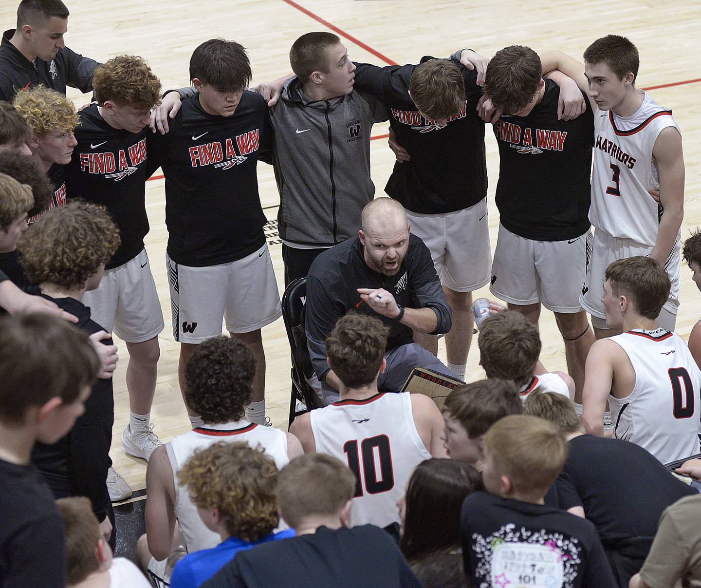 Woodland boys basketball head coach Connor Kaminke (center) talks things over with his Warriors during their regional championship win over Newark on Friday, Feb. 27, 2026, at the Warrior Dome in rural Streator.