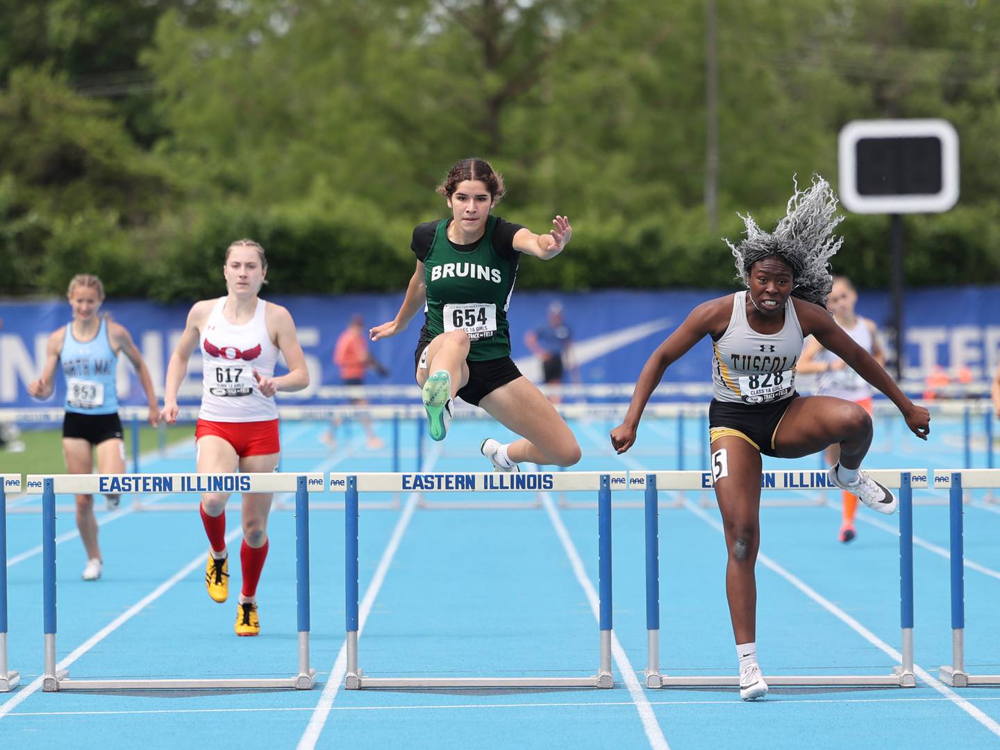 St. Bede’s Lily Bosnich, center, clears the final hurdle just behind Tuscola's Lia Patterson in the 300 m hurdles during the IHSA Class 1A Girls Track & Field State Finals on Saturday, May 24, 2025.