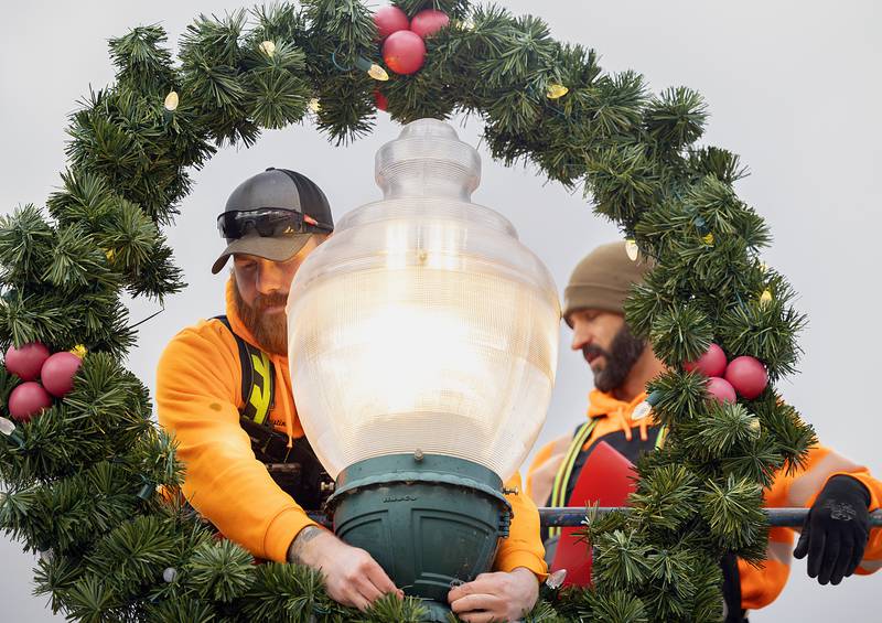 Austin Clark (left) and Steve Fassler wire up a wreath and bow Wednesday, Nov. 20, 2024, in downtown Dixon. The city will hold their annual Christmas Walk on Dec. 6.