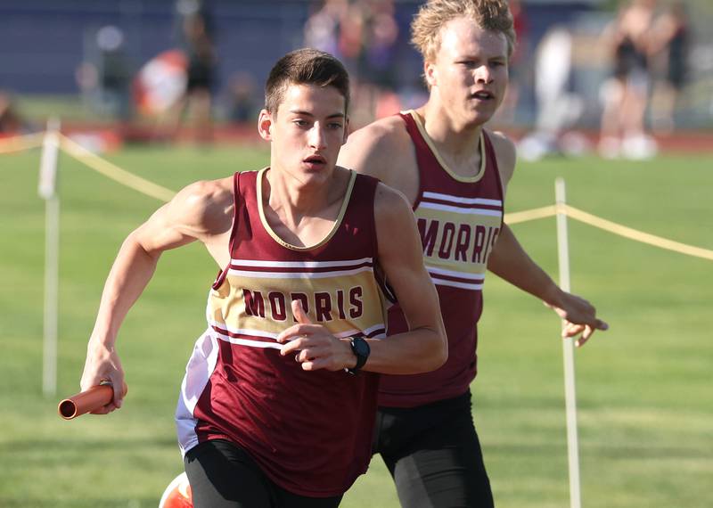Morris’ Cuyler Swanson (left) takes the handoff from Nikita Hovious in the 4x800 meter relay Tuesday, May 13, 2025, during the Interstate 8 Conference boys track championships at Rochelle High School. Morris would go on to win the relay.