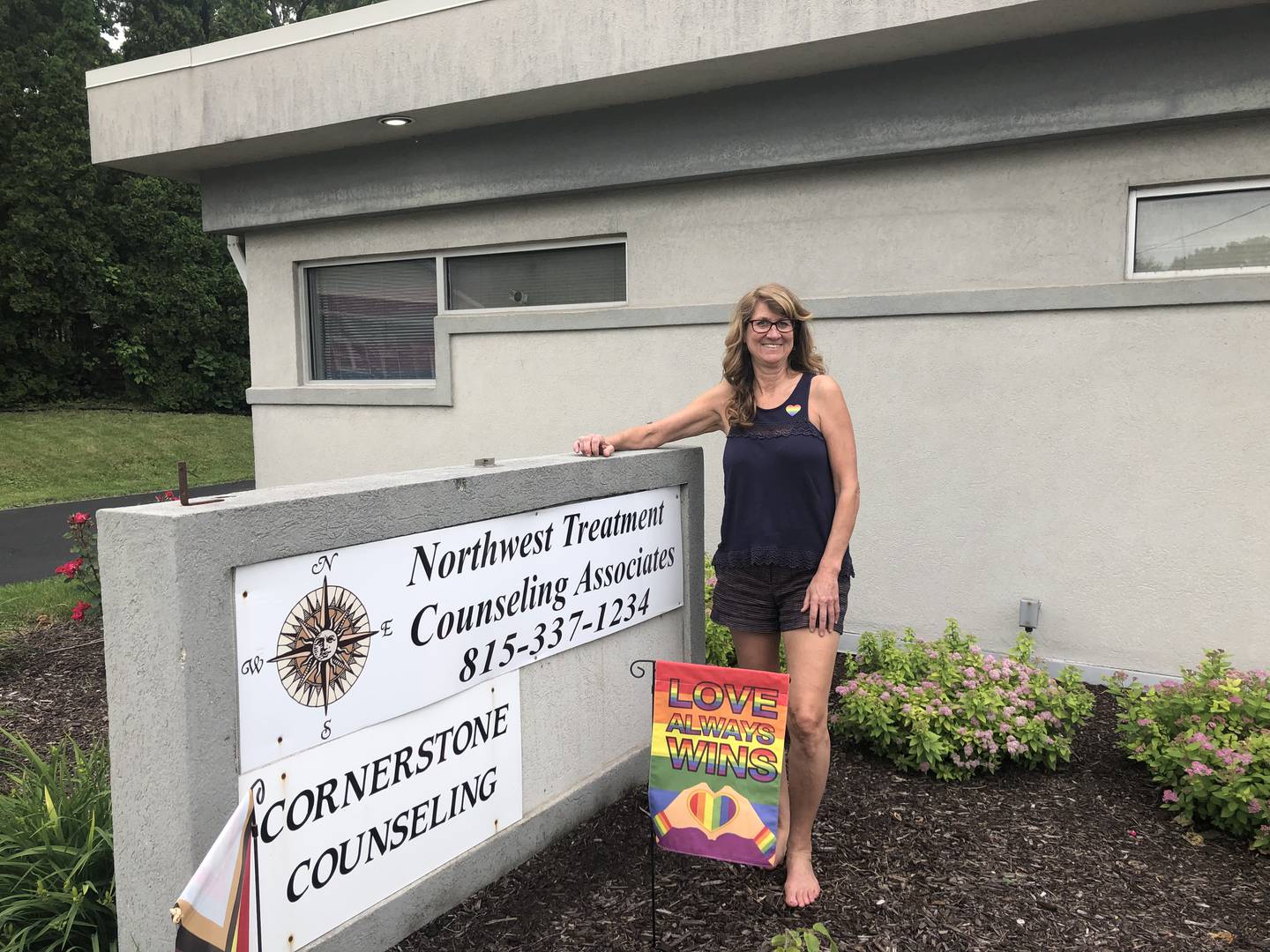 Counselor Carol Fetzner of Northwest Treatment Counseling Associates displays pride flags at the business and said she respects her neighbor's right to fly his flag upside down even if they have differing views. She's pictured on June 4, 2024.