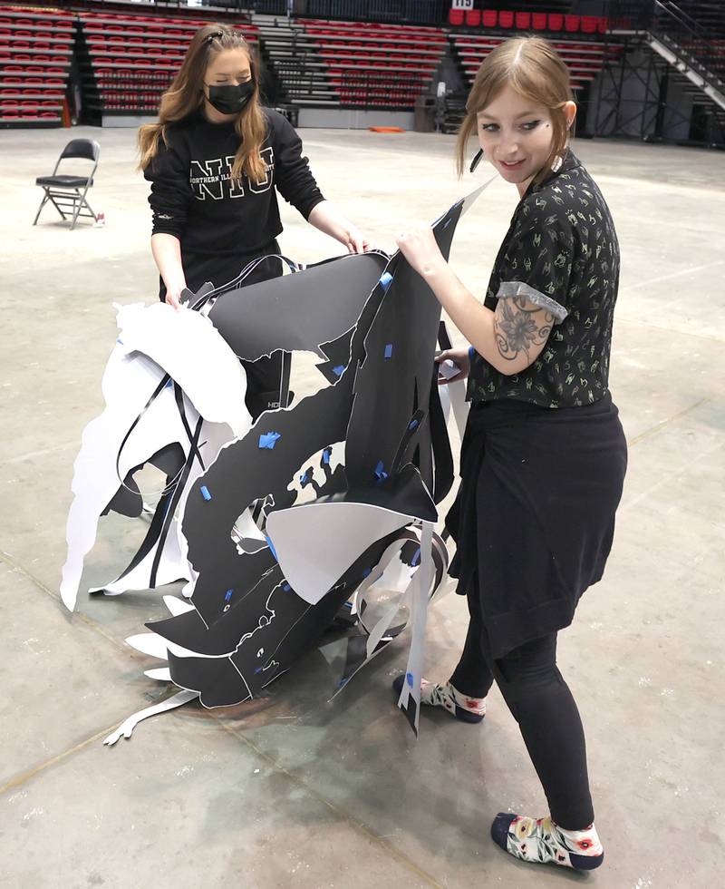 Northern Illinois University photography students Maeve Wallace (left) and Mikayla Shuster, both seniors, remove the templates from the giant paper snowflake they are making with their photography classmates Tuesday, March 29, 2022, in the Convocation Center at NIU in DeKalb. The students are attempting to break the world record for the largest paper snowflake.