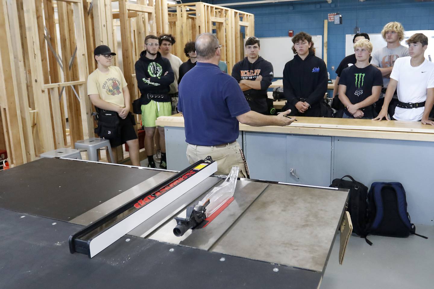 Dan Rohman teaches his construction trades students how to measure out a board to build a stud wall on Tuesday, Aug. 30, 2022, during class at McHenry High School. The students in the class will build the tiny shops that will house incubator retail businesses on McHenry's Riverwalk at Miller Point.