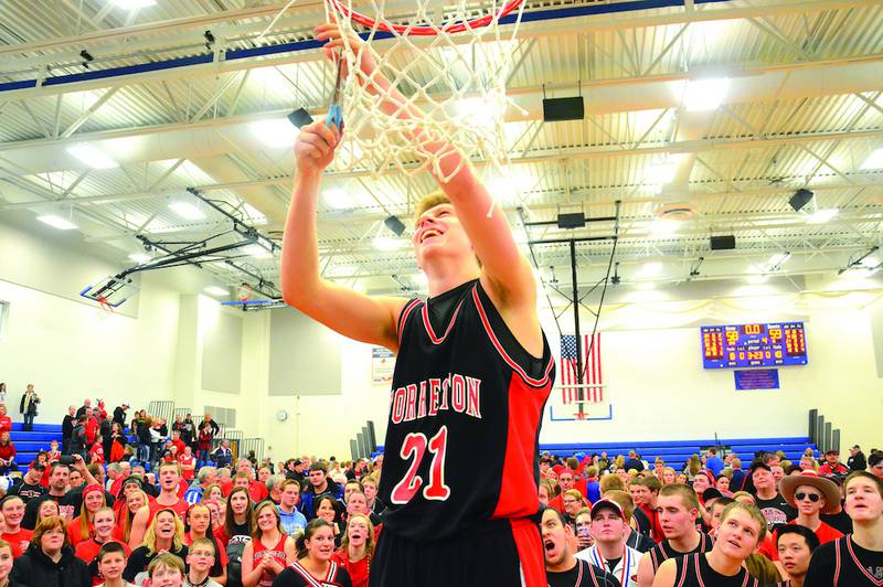 Forreston's Kaleb Reining cuts down a piece of the net while the team and fans watch on after the Cardinals won the Eastland Sectional 59-58 over Freeport Aquin. Photo by Chris Johnson