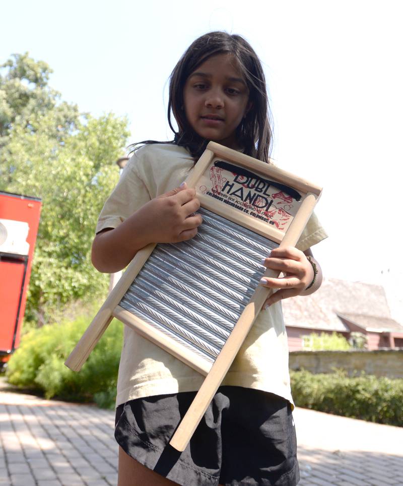Children including Lena Babul of Glen Ellyn tests her storming skills on a washboard provided by The Old Town School of Folk Music during the Glen Ellyn Art Festival on Sunday, Aug 24, 2024 at Lake Ellyn.