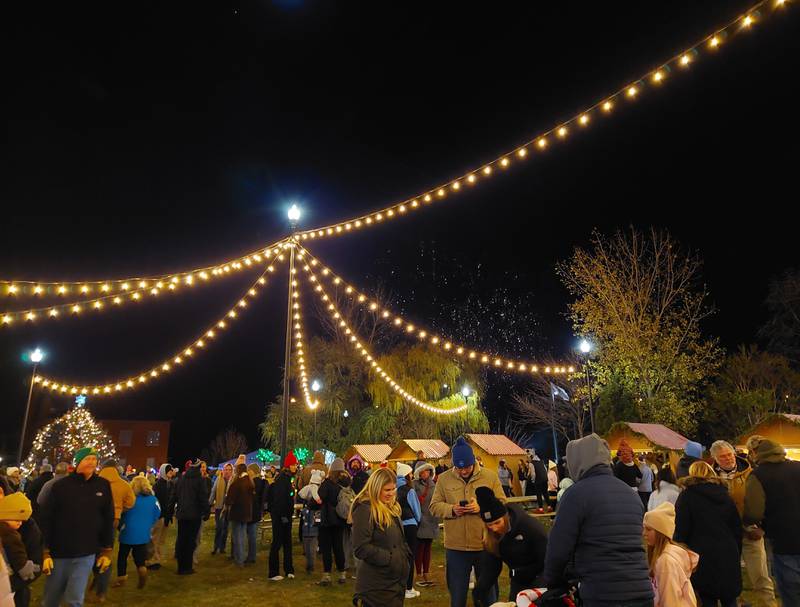 Visitors shop at the Chris Kringle Market on Friday, Nov. 24, 2023, as a fireworks display goes off behind them in the Jordan block in Ottawa.