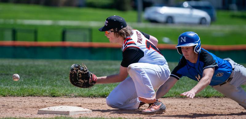 St. Charles North's Christopher Graziano (8) attempts to avoid a pickoff play by diving back to first against St. Charles East's Ian Paprocki (14) during a baseball game at St. Charles East High School on Saturday, May 7, 2022.