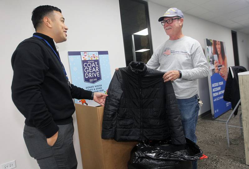 Josue Cruz, of Gurnee, branch manager, talks with Terry Devanie, of Libertyville, director of the Midwest Veterans Closet, about some of the coats that were donated and put inside a collection box as he makes a stop to collect them for the GLMV 2022 Coat Drive for Vets at the Great Lakes Credit Union in Libertyville. Devanie is a Navy veteran. GLMV is the Chamber of Commerce for Green Oaks, Libertyville, Mundelein and Vernon Hills.