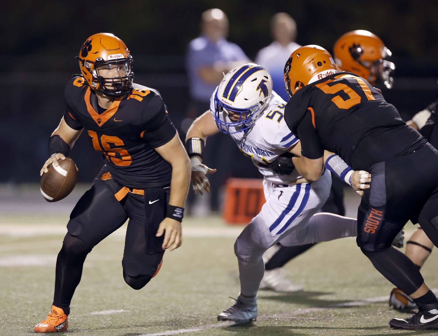 Wheaton Warrenville South's Justin Miller (16) moves out of the pocket looking for a teammate at Wheaton North's Rob Razzino (54) pursues him Friday, Oct. 3, 2025 at Red Grange Field in Wheaton.