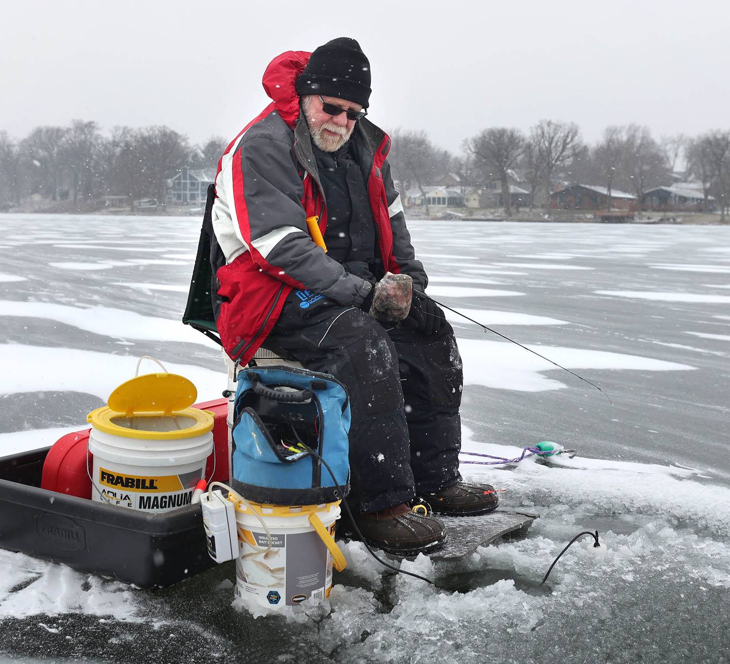 Eugene Wilson, of Montpelier, OH, who is in town visiting his daughter and son-in-law, who live in Lake Holiday, tries his luck fishing through the ice Thursday, Dec. 22, 2022, on Lake Holiday in Sandwich. Snow, frigid temperatures and wind rolled into the area Thursday making travel and any outdoor activity a challenge.
