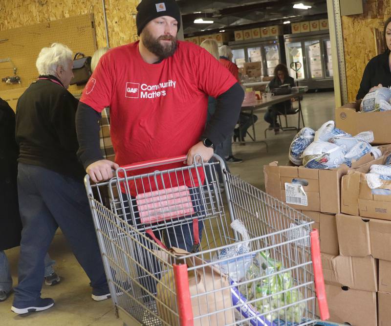Evan Smith employee at GAF, volunteers by pushing a cart of groceries outside of the Illinois Valley Food Pantry during the Thanksgiving Distribution on Wednesday, Nov. 19, 2025 at the Illinois Valley Food Pantry in Peru. Nearly 500 families or roughly 1,200 people in the Illinois Valley got a Thanksgiving meal.
