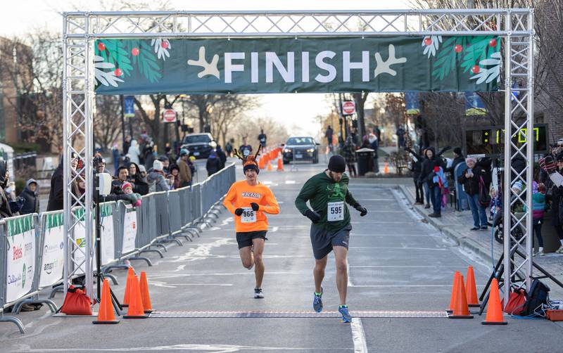 Patrick Austin, right, runs past the finish line to take first place in the 13th annual Lions Charities Reindeer Run 5K Wheaton on Saturday, Dec. 7, 2024.