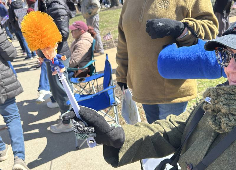 A demonstrator holds a toilet brush fashioned after Donald Trump during the No Kings rally on Saturday, March 28, 2026, in downtown Oregon, Illinois.