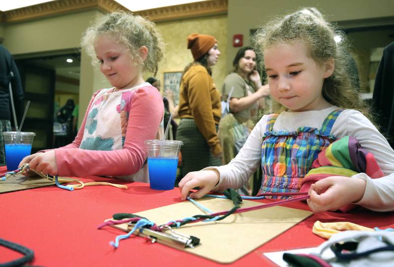 Ellie Langley, (left) 7, and Loretta Cima, 6, both from DeKalb, make jewelry using upcycled T-shirts Thursday, April 18, 2024, during Earth Fest at the Egyptian Theatre in DeKalb. The event, in honor of Earth Week, was presented by DeCarbon DeKalb, in partnership with NIU.