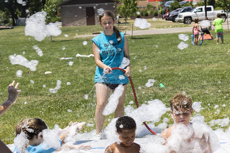 Camp leader Elena Refatllari sprays down kids Tuesday, June 18, 2024 enjoying the foam gun at SPARK Camp.