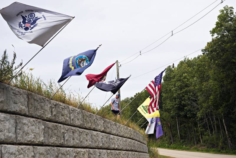 Tanner Brainerd unfurls flags along Crosby road in Morrison. The flag display earned Ken Brainerd a special award from the Morrison American Legion.