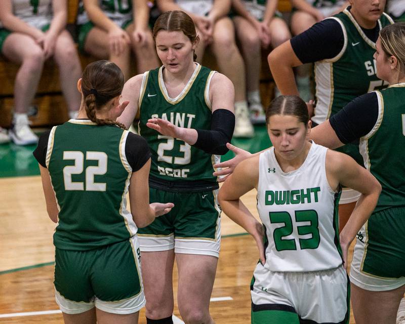 St. Bede's Lili McClain (23) high-fives teammate Hannah Heiberger (22) after scoring as Makayla Wahl-Seabert (23) of Dwight walks off in disappointment on Monday, January 19, 2026 at the Krese Memorial Gymnasium in Dwight.