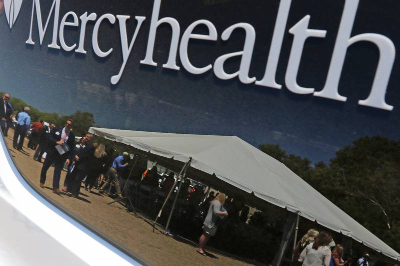 Attendees are seen in a reflection on a Mercyhealth vehicle during a groundbreaking ceremony for a new Mercyhealth hospital at the intersection of Three Oaks Road and Route 31 on Wednesday, June 16, 2021, in Crystal Lake.
