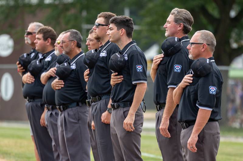 Umpires put hand over heart during the National Anthem performance on Friday, July 11, 2025 at Washington Park in Peru.