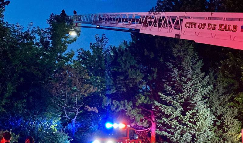 DeKalb firefighters are hoisted into the air on a ladder truck to help provide light to emergency divers undertaking a water rescue on Sunday, July 27, 2025, in the 600 block of Ridge Drive in DeKalb.