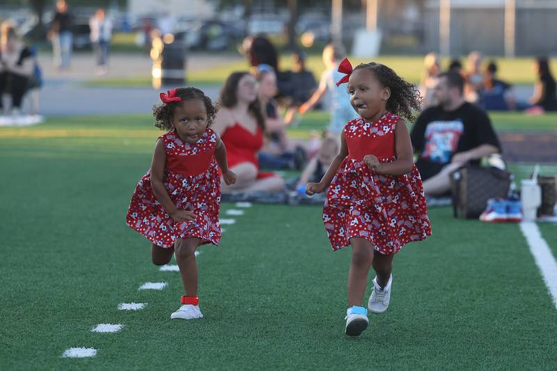 Charlotte, left, and her twin sister Callie, four-years-old, run on the field before the start of the fireworks at Joliet Memorial Stadium in on Thursday July 4, 2024.