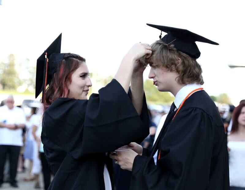 St. Charles East graduate Ariana Rivera helps Calvin Post with his cap before the school’s 2023 commencement ceremony at Northern Illinois University in DeKalb on Monday, May 22, 2023.