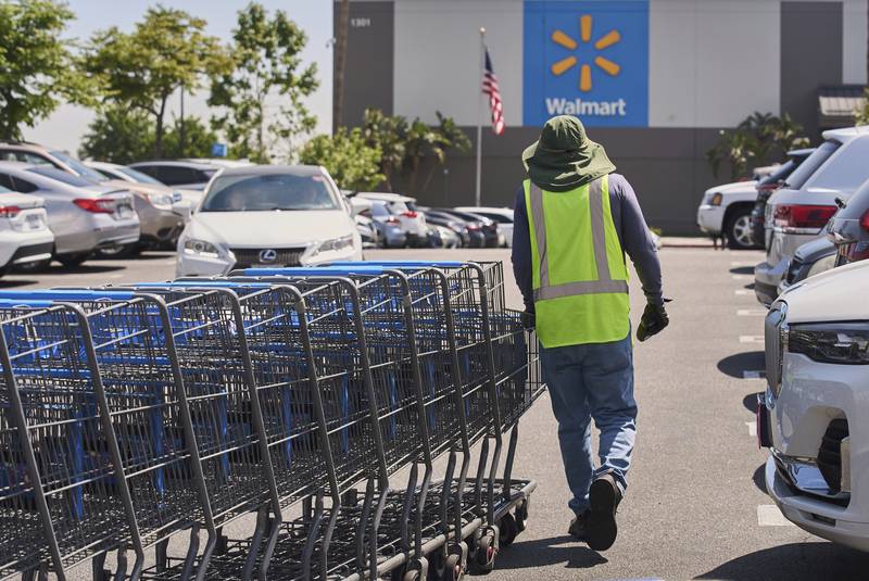 FILE - Empty shopping carts are collected from the parking lot at Walmart store in Burbank, Calif., on Thursday, April 10, 2025. (AP Photo/Damian Dovarganes, File)