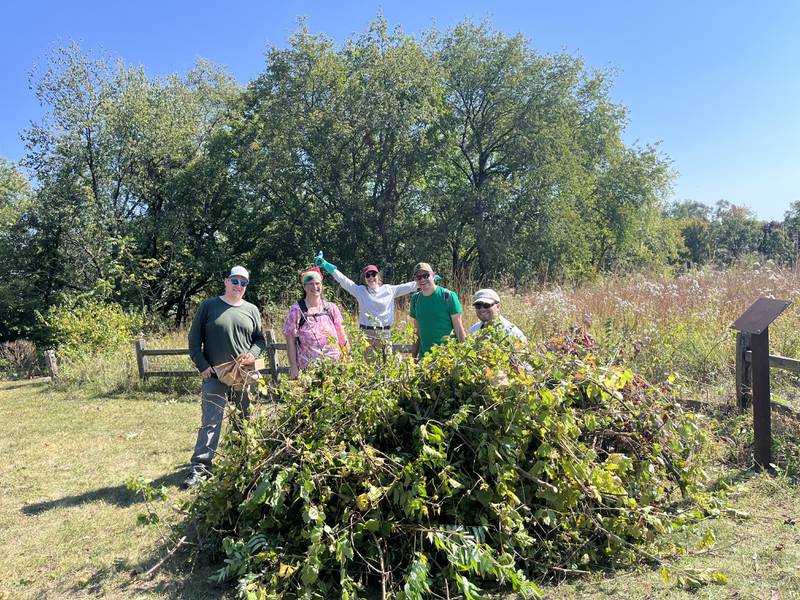 Cary Prairie Stewards (from left to right) Mike Burke, Ruth Krevitt, Ellie Krall, Jay Krall and Jacob Karkowski standing behind a pile of invasive brush cleared from Hillside Prairie in Cary on Sept. 28th, 2025.