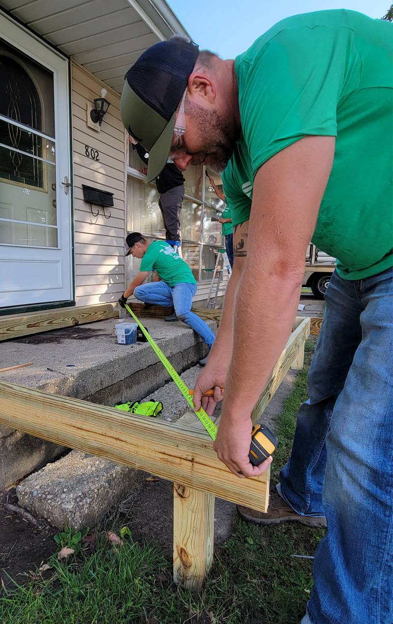 Labor of Love volunteers Ryker Terry (left) and his father, Justin Terry, measure the framework for a new porch being built on a south Ottawa home on Saturday.