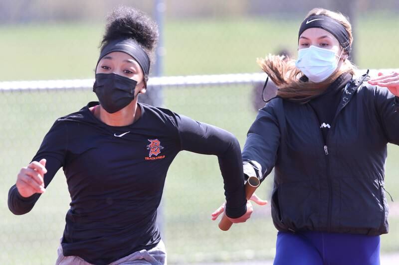 DeKalb sophomore Sariyah Watson takes the handoff from junior Becca Shank as they work on running relays Thursday afternoon during girls track practice at the school.