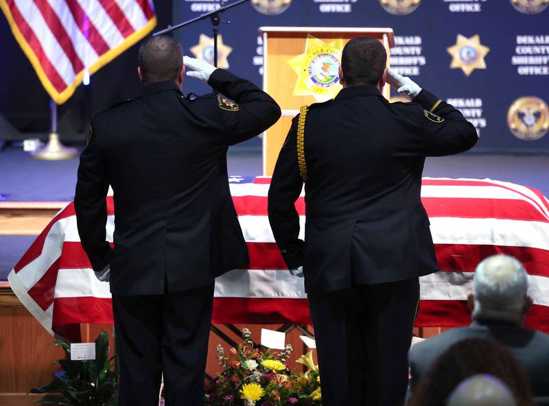 DeKalb County sheriff’s deputies salute the casket of former DeKalb County Sheriff Roger Scott during the memorial service for the former sheriff Friday, March 7, 2025, at Bethany Road Bible Church in DeKalb. Scott, who was the county sheriff for 36 years, died on February 23 at the age of 78.