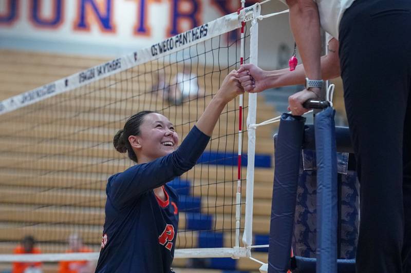 Oswego’s Ava Flanigan (12) fist bumps an official prior to the start of the second set during a volleyball match against Minooka at Oswego High School on Thursday, Oct. 3, 2024.